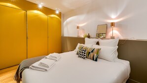 Ein Hotelzimmer mit einem Bett, weißen Leinen, einer braunen Tagesdecke und einem gelben Kleiderschrank.