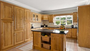 A spacious kitchen with wooden cabinets, a central island with baskets, and a window providing natural light.