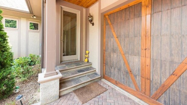 A house entrance with a wooden door, a stone staircase, and a large wooden garage door.