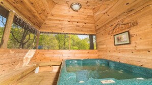 Une cabane en bois avec un jacuzzi, une pancarte de bienvenue et un tableau encadré accroché au mur.