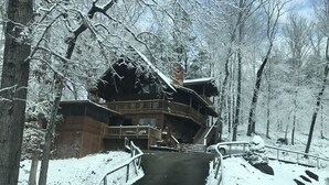 Une cabane en bois dotée d’un balcon, entourée d’arbres couverts de neige.