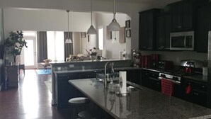 Eine moderne Küche mit einer zentralen Kochinsel, Edelstahlgeräten und Pendelleuchten.