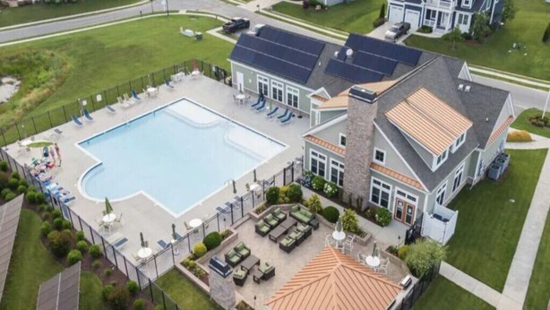 Ein Wohnhaus mit Schwimmbad, Sitzgelegenheit im Freien und einer überdachten Terrasse.