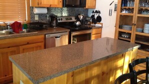 A kitchen with wooden cabinets, granite countertops, a microwave, stove, and a cabinet with glassware. - Pet Friendly Circle 4 Cabin And People Friendly As Well (Sunriver)