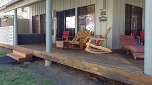 A wooden porch with outdoor seating, including a rocking chair and two chairs with cushions. - Pet Friendly Circle 4 Cabin And People Friendly As Well (Sunriver)