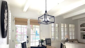 A dining area with a round wooden table, black chairs, and a hanging light fixture. - Winter dates going fast! Beautifully renovated 3bd/3bth poolside, mountain views (La Quinta)