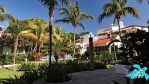 A resort with palm trees, a pool, and a building with a red roof. - Private Beachfront w/ Lanai-Pool-Tropical Gardens! (Akumal)