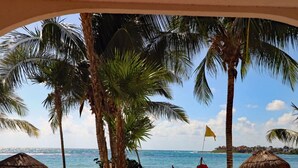 A beach view with palm trees, a lifebuoy, and a thatched umbrella. - Private Beachfront w/ Lanai-Pool-Tropical Gardens! (Akumal)