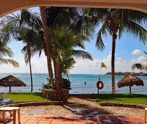 A beach view with palm trees, a lifebuoy, and a thatched umbrella. - Private Beachfront w/ Lanai-Pool-Tropical Gardens! (Akumal)