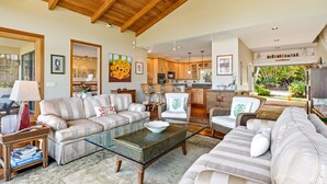 A spacious living area with a high ceiling, a glass coffee table, and a comfortable seating arrangement.
