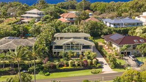 A residential area with multiple houses, lush greenery, and a view of the ocean.