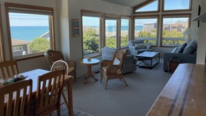 Ein gemütliches Wohnzimmer mit Essbereich, großen Fenstern mit Meerblick und einer bequemen Sitzecke.