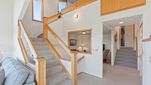 Eine Treppe mit Holzwangen und Teppichstufen führt zu einer zweiten Etage mit Fenster und Lampe.