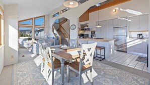 Eine geräumige Küche mit modernen Geräten, ein Essbereich mit Holztisch und -stühlen sowie eine Treppe, die zu einer oberen Ebene führt.
