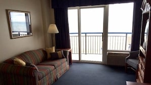 Ett rum med en randig soffa, en lampa, en stol och ett stort fönster med utsikt över havet.