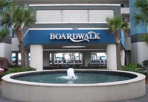 A hotel named BOARDWALK with a central fountain, palm trees, and a pool area.