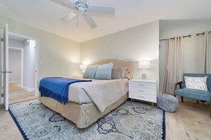 A bedroom with a bed, bedside tables, a chair, a rug, and a ceiling fan.
