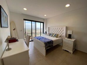 A bedroom with a bed, a desk, a chair, a nightstand, and a surfboard.