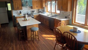A spacious kitchen with wooden cabinets, a large island, and a dining area with a table and chairs. - 3,500 sq ft MAIN LAKE - deep water, boat house, hot tub & beach! (Henrico)