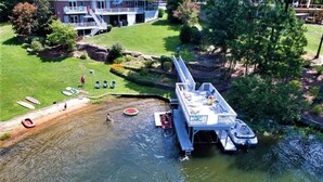 An aerial view of a lakeside property with a dock, kayaks, and a building with a deck. - 3,500 sq ft MAIN LAKE - deep water, boat house, hot tub & beach! (Henrico)