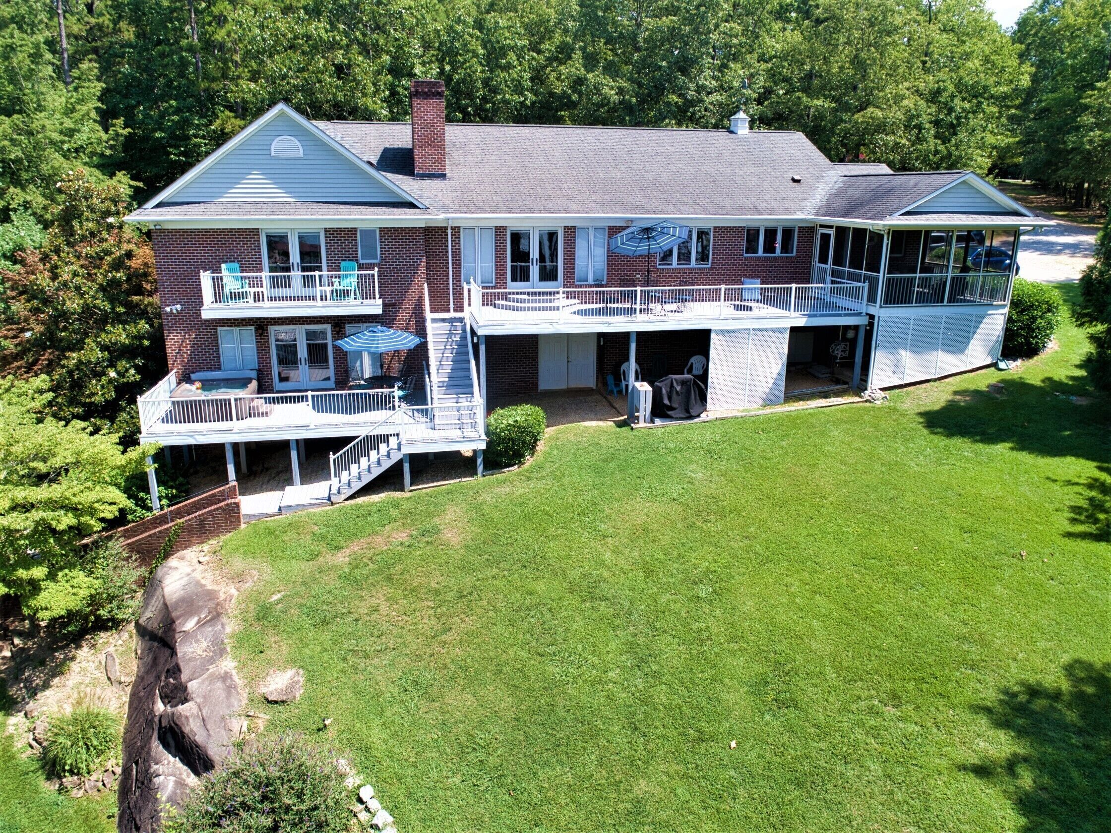 A two-story house with a large front porch, a covered patio, and a backyard.