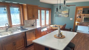 A kitchen with wooden cabinets, a white countertop, and a central island with bar stools. - 3,500 sq ft MAIN LAKE - deep water, boat house, hot tub & beach! (Henrico)