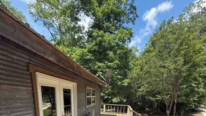 A wooden deck with a railing, a door, and a window. - Camp House on Red Creek - Uncle Ralph’s Cabin Rentals - PRIVATE BEACH (Perkinston)