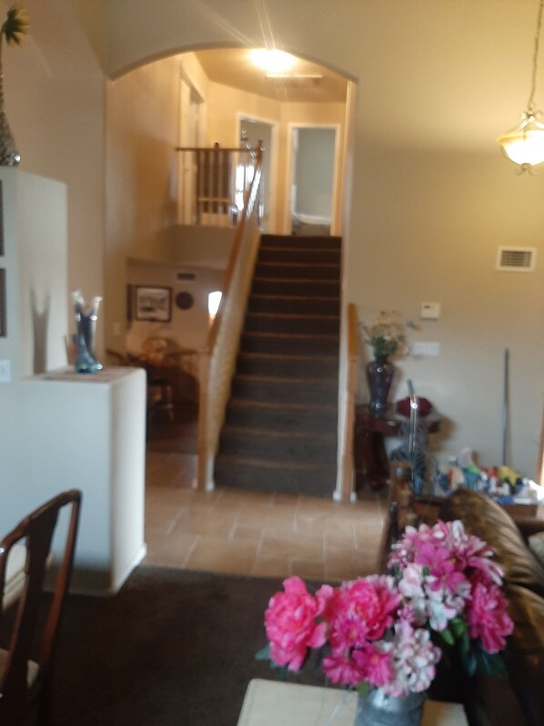 A staircase leading to a second floor, a dining area with a table and chairs, and a vase with flowers on the floor. - Gorgeous Glendale Home Sleeps 10 Pool, Hot Tub, (Glendale)