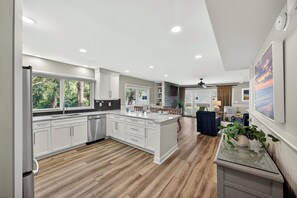 Una cocina moderna con armarios blancos, una isla central y un comedor con un sofá azul.