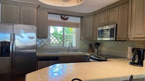 Una cocina con electrodomésticos de acero inoxidable, una ventana con un ángel decorativo y un salpicadero de azulejos.
