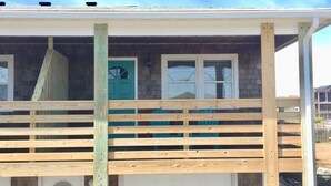 A house under construction with a wooden deck and a garage door. - Atlantic Oasis, less than 1 block to the beach! Private & Spacious, Full Kitchen (Nags Head)