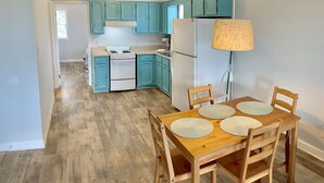A kitchen with teal cabinets, a white stove, and a dining table with four chairs. - Atlantic Oasis, less than 1 block to the beach! Private & Spacious, Full Kitchen (Nags Head)