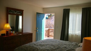 A bedroom with a bed, dresser, mirror, and a door leading to a balcony.
