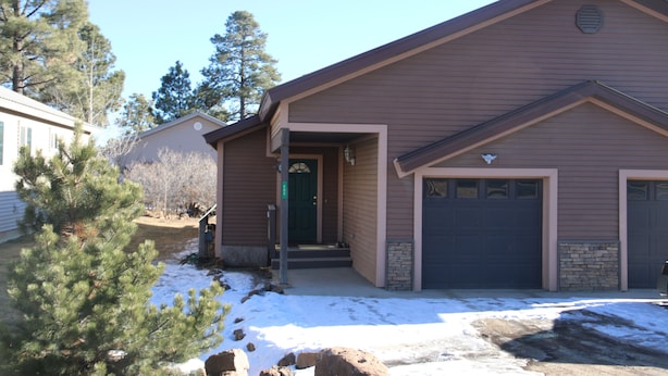 A two-story house with a brown exterior, a front porch, and a garage.