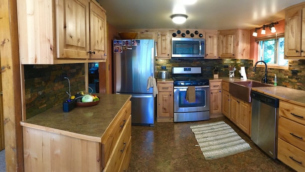 Una cocina con armarios de madera, un refrigerador de acero inoxidable, un horno, un microondas y un lavavajillas.