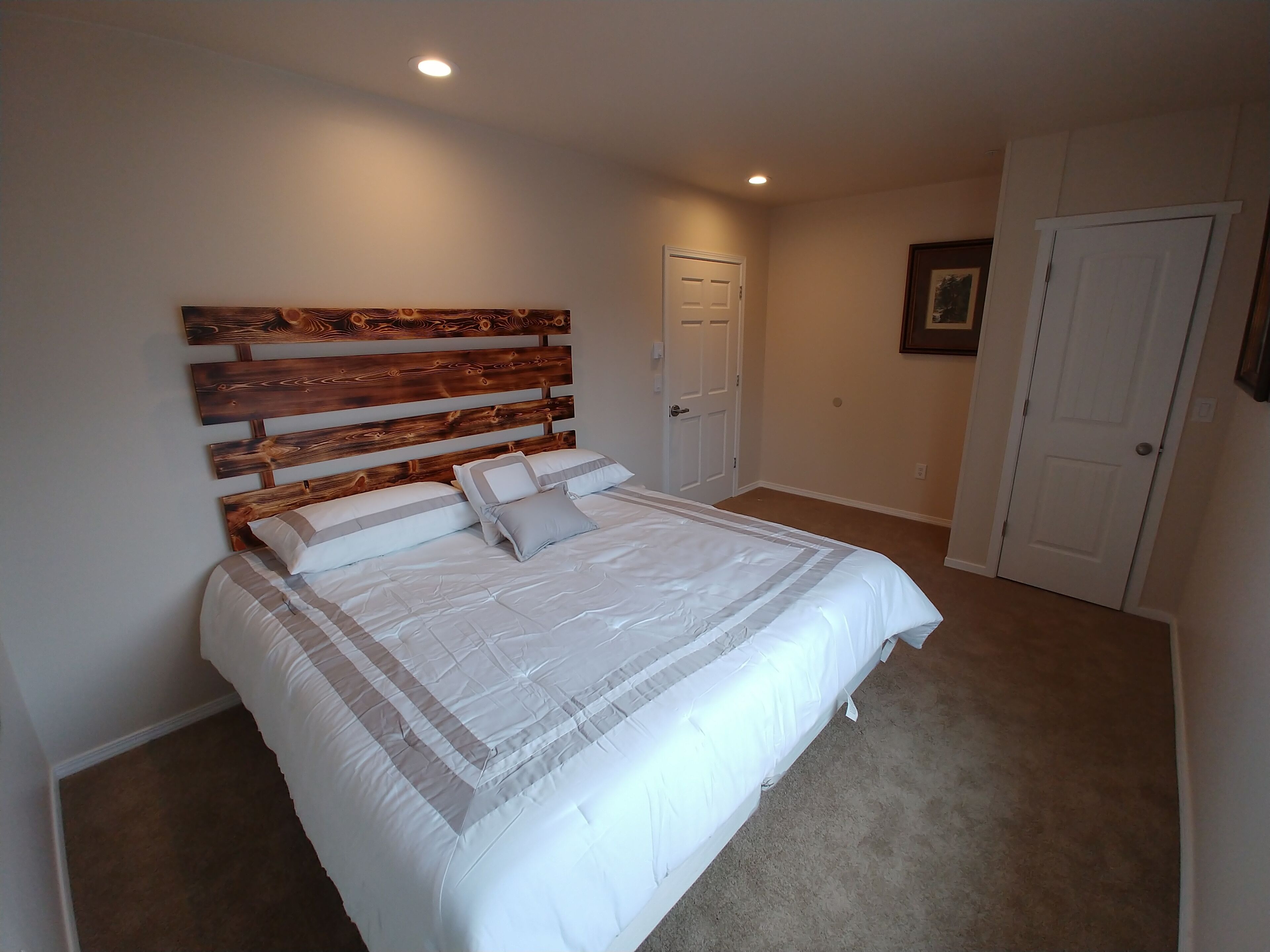 A bedroom with a large bed, a wooden headboard, and a carpeted floor.