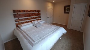 Un dormitorio con una cama grande, cabecera de madera y piso alfombrado.