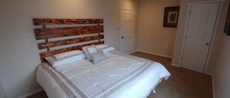 A bedroom with a large bed, a wooden headboard, and a carpeted floor.