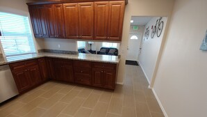 Una cocina con armarios de madera, encimeras de granito y piso de baldosas.
