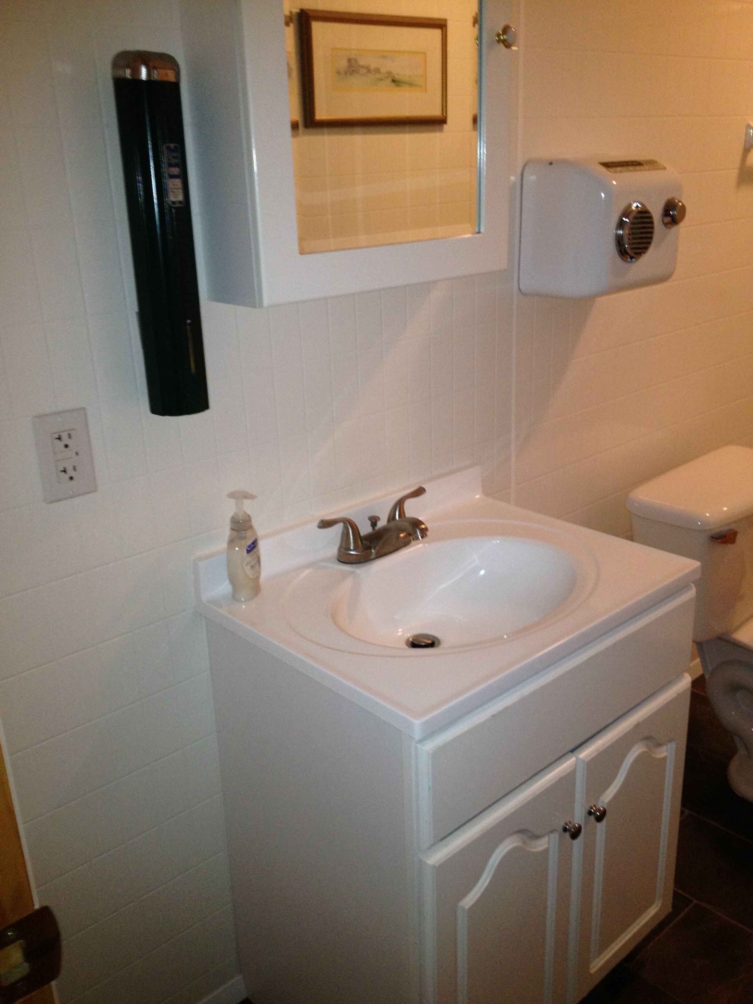 A bathroom with a white sink, a toilet, and a wall-mounted heater.