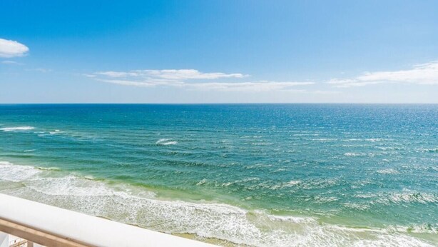 A clear view of the ocean from a balcony with a railing, a clear sky, and a calm sea. - Pet Friendly-Beach Front- West Corner Condo-2 Pools (Gulf Shores)
