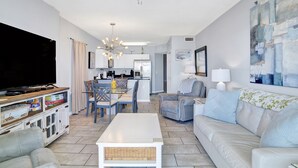 A spacious living room with a television, sofa, and dining area. - Pet Friendly-Beach Front- West Corner Condo-2 Pools (Gulf Shores)