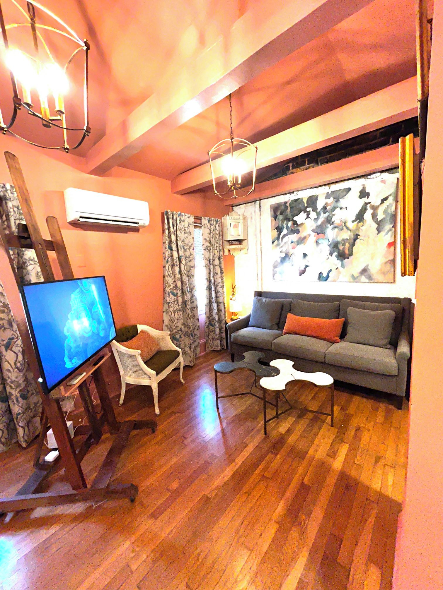 A living room with a flat-screen TV, a sofa, a coffee table, and a wooden floor.