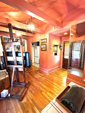 A room with wooden flooring, a television, a painting, and a mirror. - Welcome to the Nest, a unique private carriage house--Great Value! (Savannah)