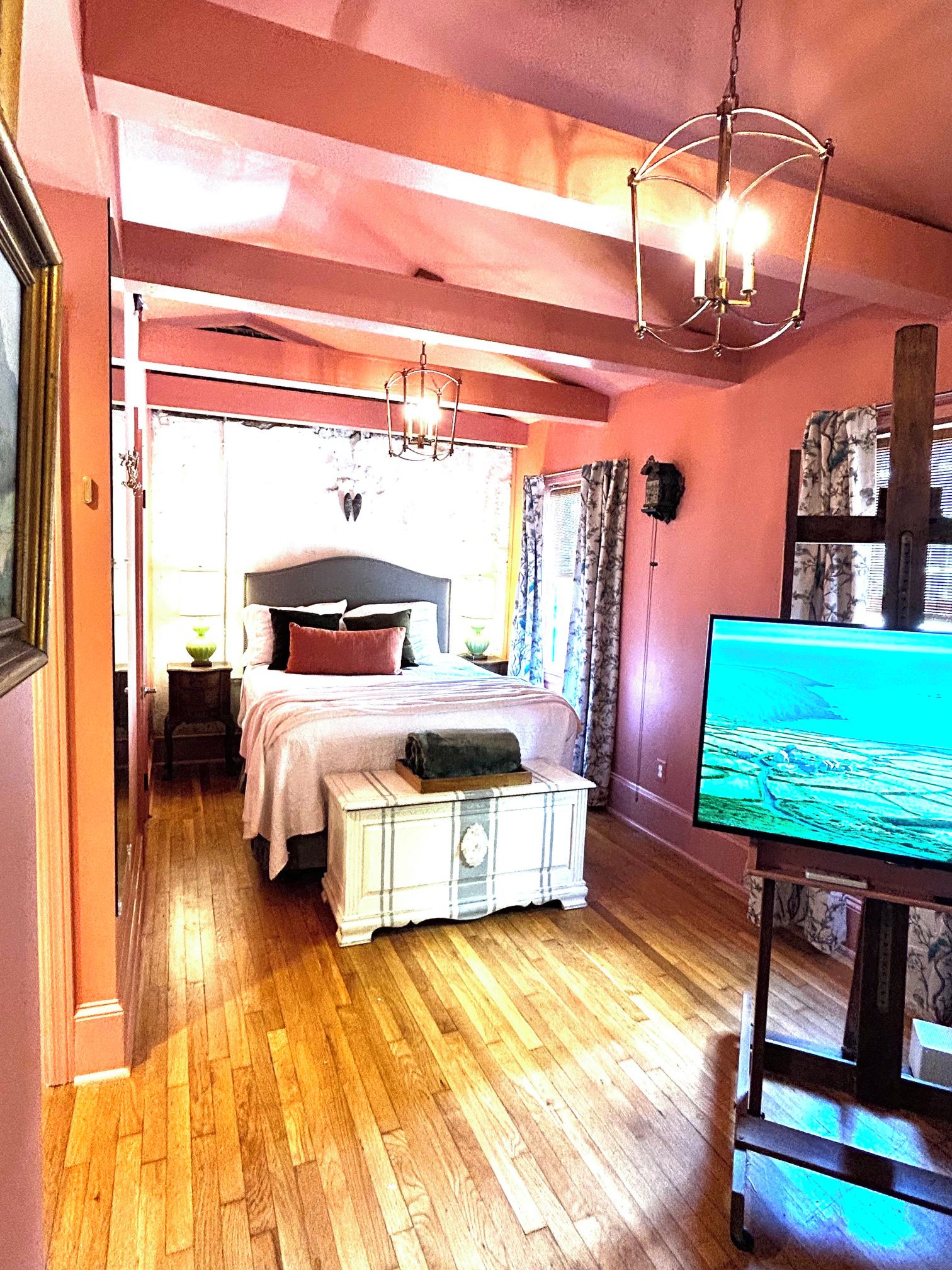 A bedroom with a bed, bedside table, lamp, and a television.