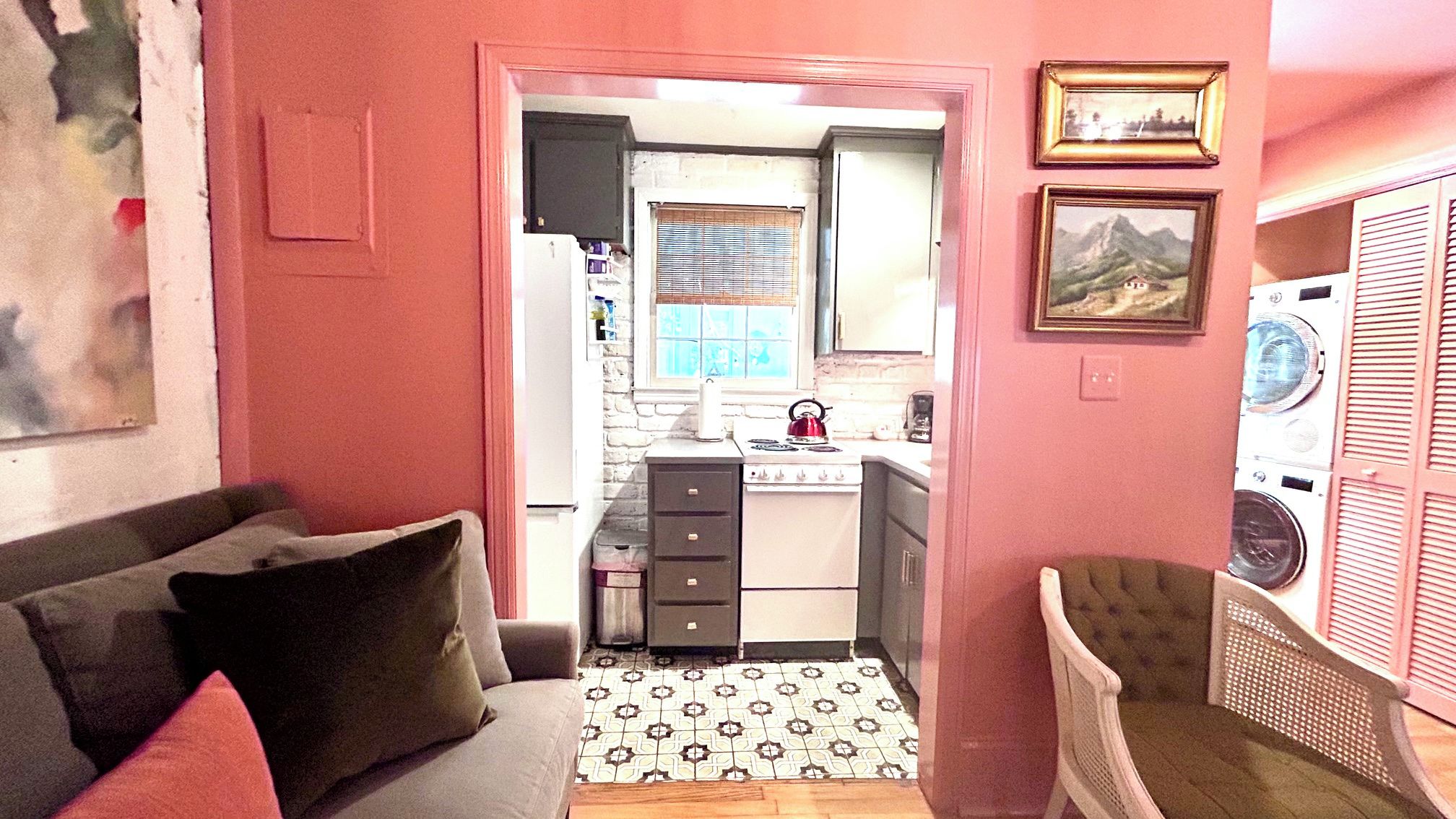 A compact living space with a kitchenette, a sofa with cushions, a patterned floor, and a chair.
