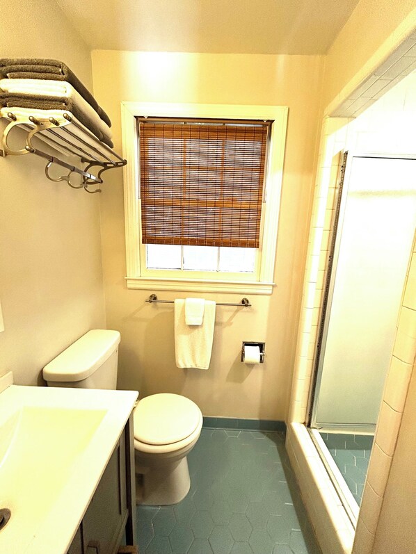 A small bathroom with a toilet, a sink, a towel rack, and a window with blinds. - Welcome to the Nest, a unique private carriage house--Great Value! (Savannah)