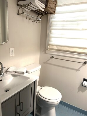 A bathroom with a white sink, a toilet, and a window with blinds. - Welcome to the Nest, a unique private carriage house--Great Value! (Savannah)