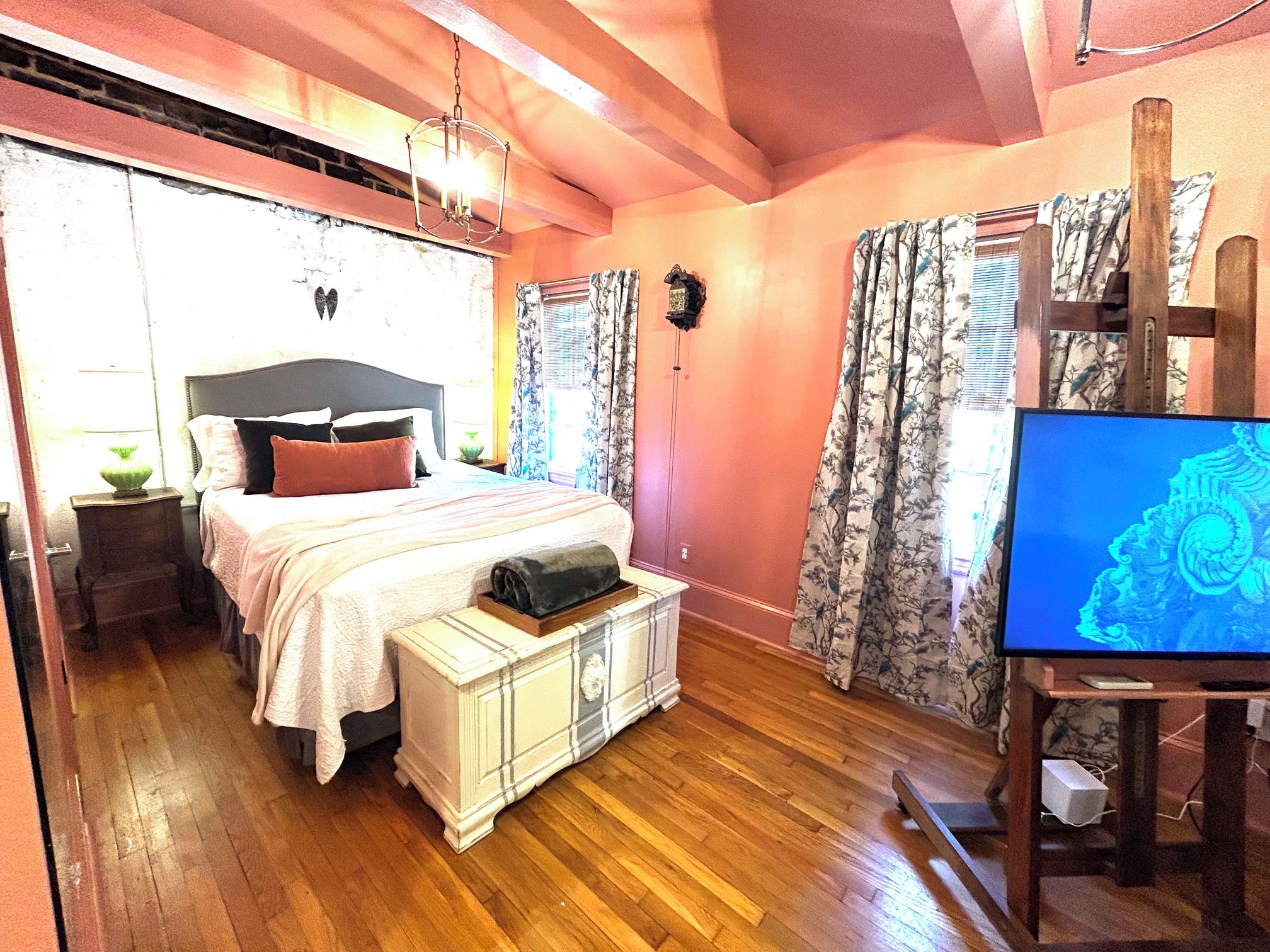 Ein Schlafzimmer mit Bett, Nachttisch, Lampe und Fernseher.