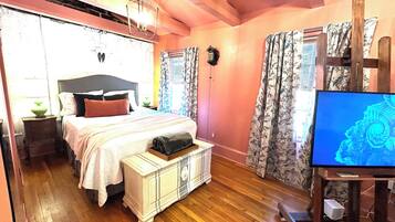 A bedroom with a bed, bedside table, lamp, and a television.